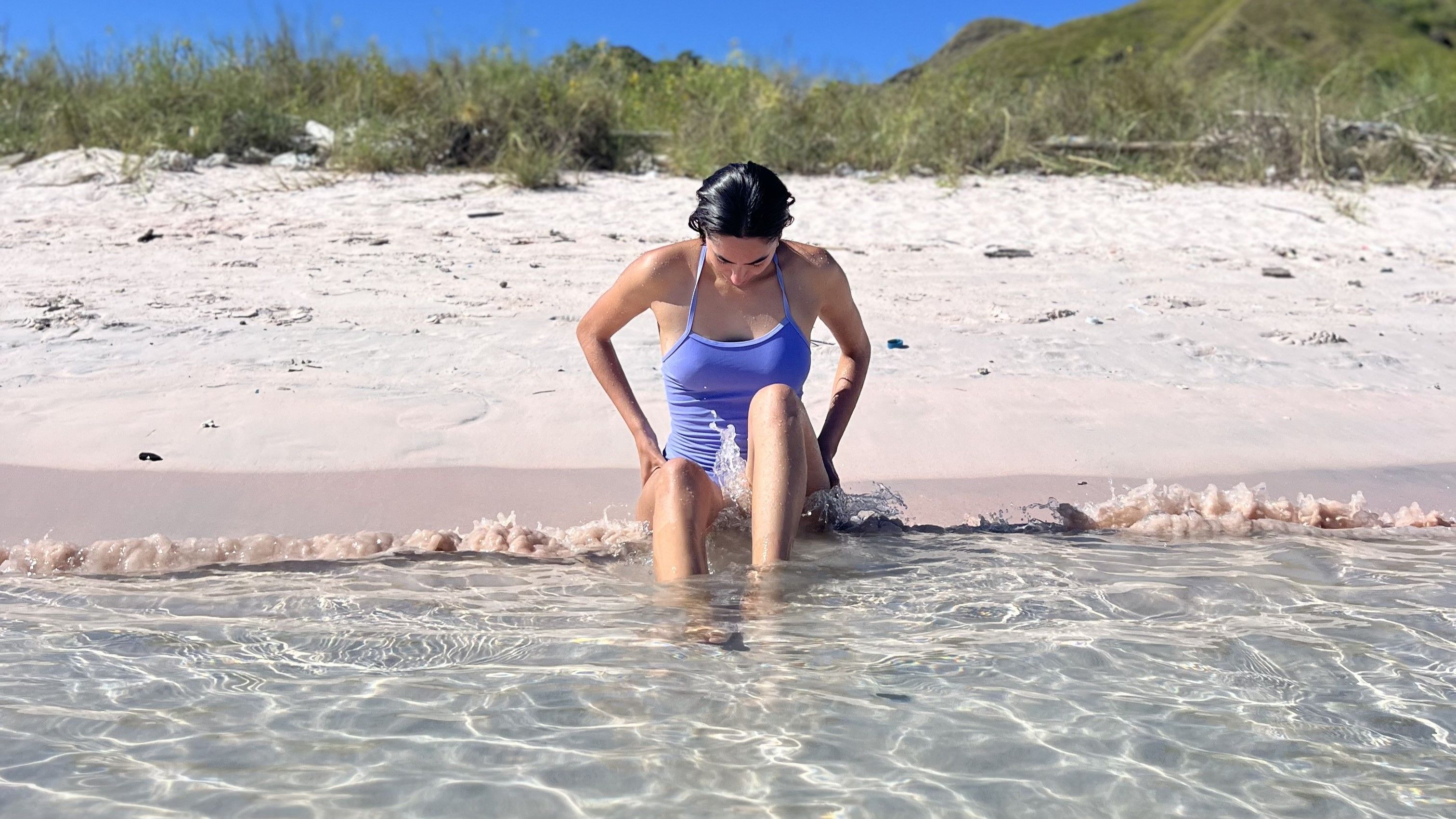 Daniela sitting on a pink sand beach