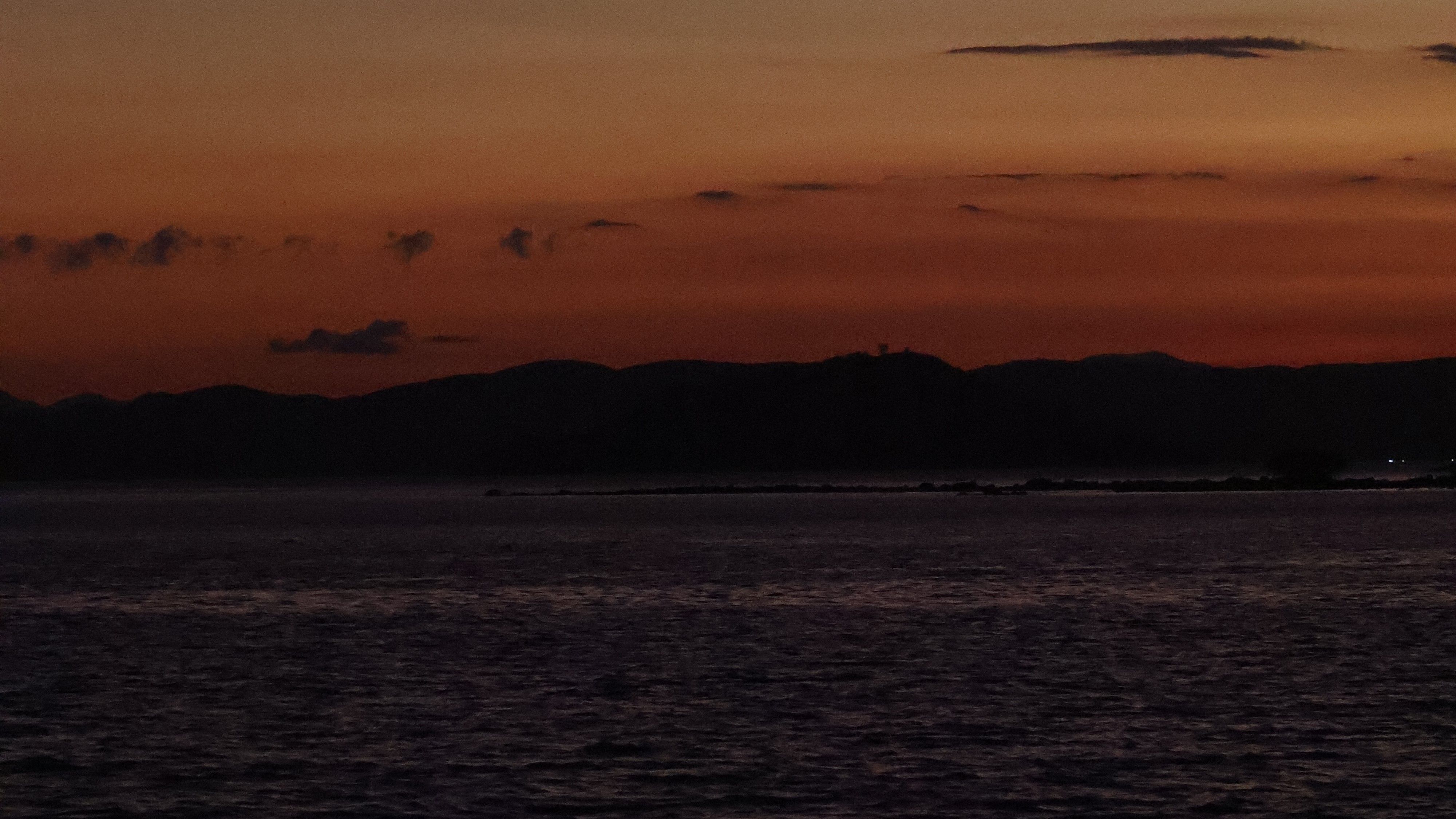Multicoloured sunset viewed over the water from the side of a boat