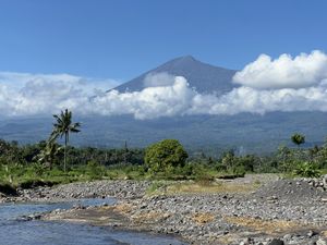 Mt. Rinjani rising over a beach between the clouds